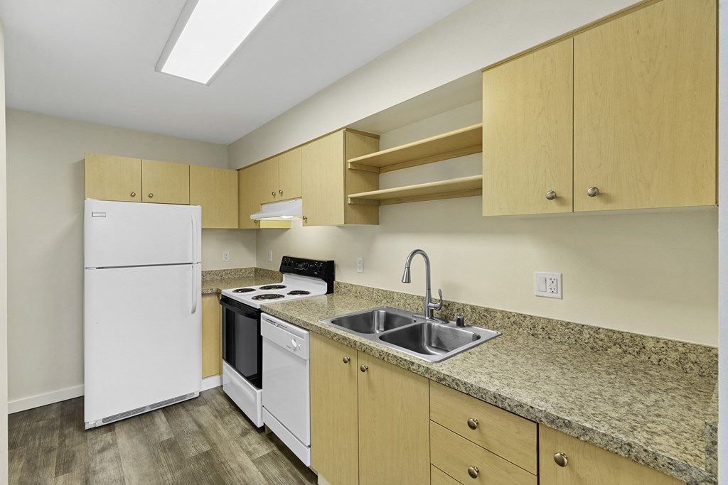 Modern Style Kitchen with Wooden Cabinetry, Plank Flooring, and White Refrigerator Modern Style Kitchen with Wooden Cabinetry, Plank Flooring, and White Refrigerator at Sir Gallahad Apartment Homes, Bellevue, Washington 98004